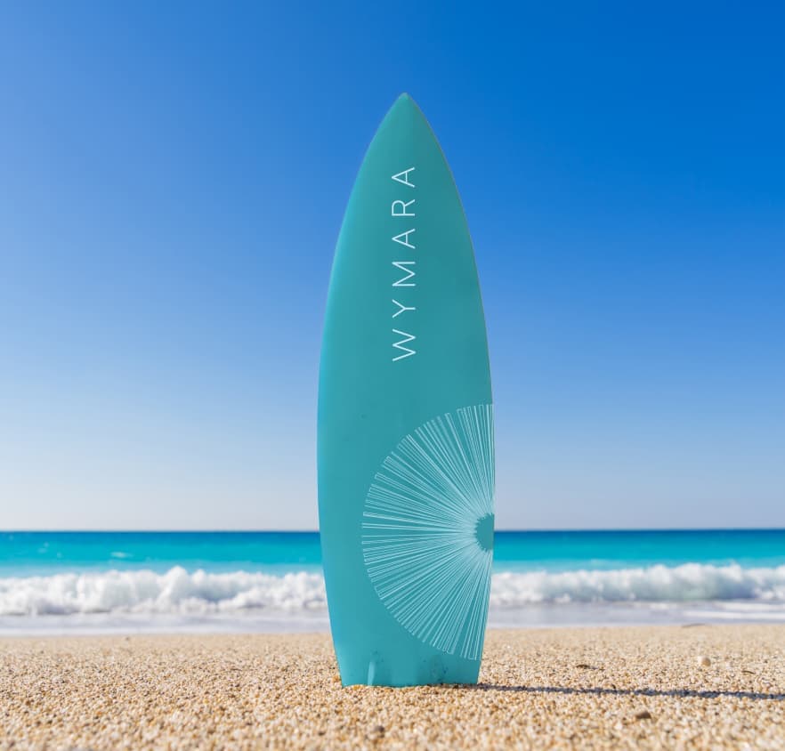 A Wymara branded surfboard sites upright on the beach