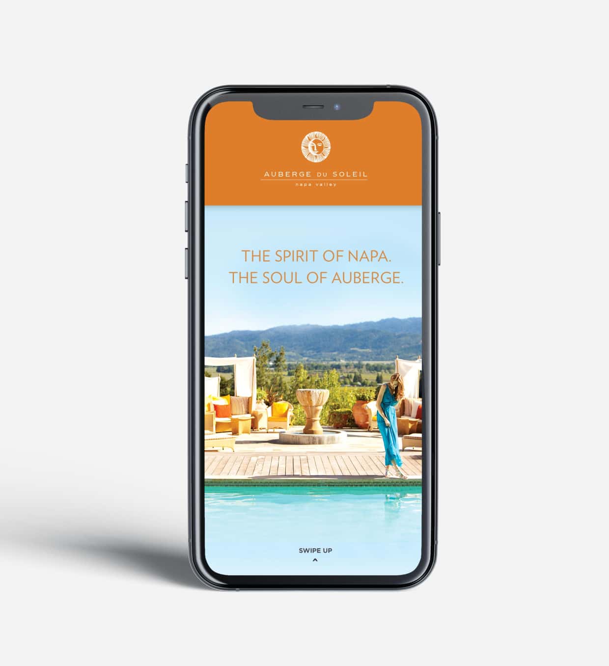 A smartphone displaying an advertisement with a poolside view at an Auberge resort, with the caption 'The spirit of Napa. The soul of Auberge.' and an invitation to swipe up.